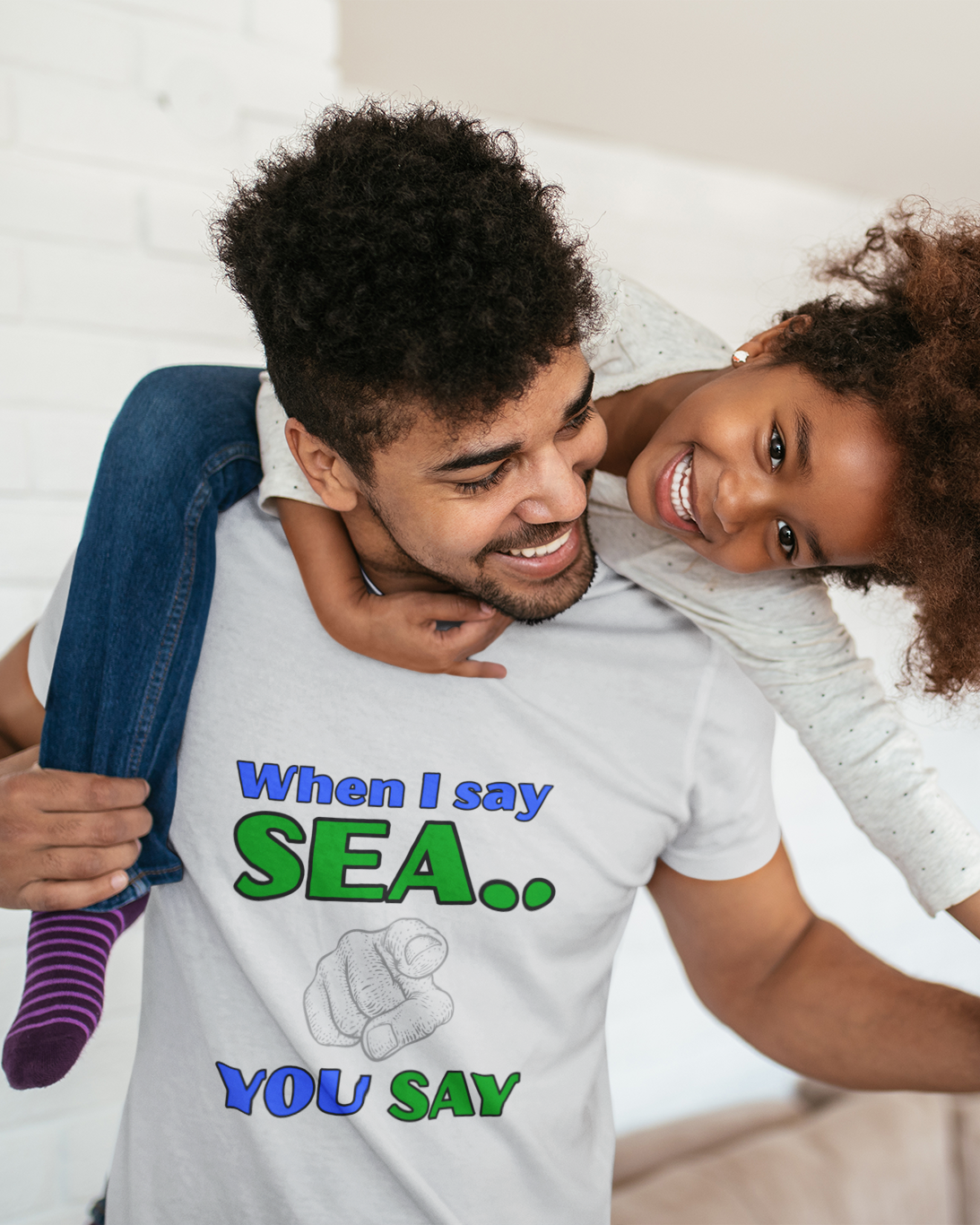 Father and daughter playing wearing a white t-shirt with WHEN I SAY SEA design