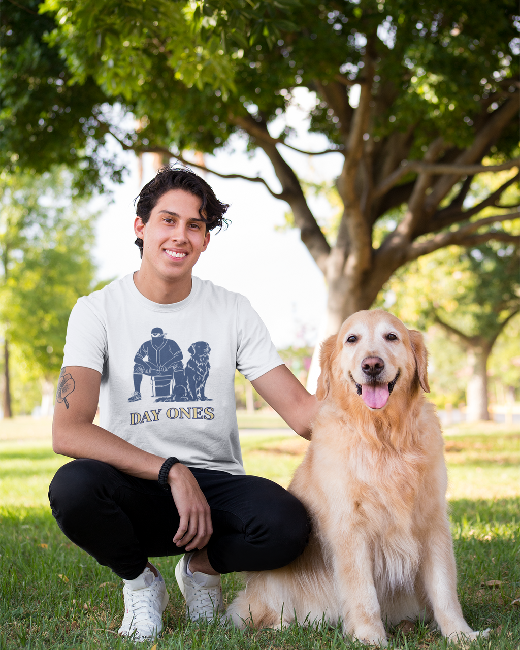 Man with a dog in a park wearing a 'Day Ones' t-shirt
