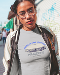 Young lady wearing a t-shirt with 'Kingdome' text and graphics on a city street.