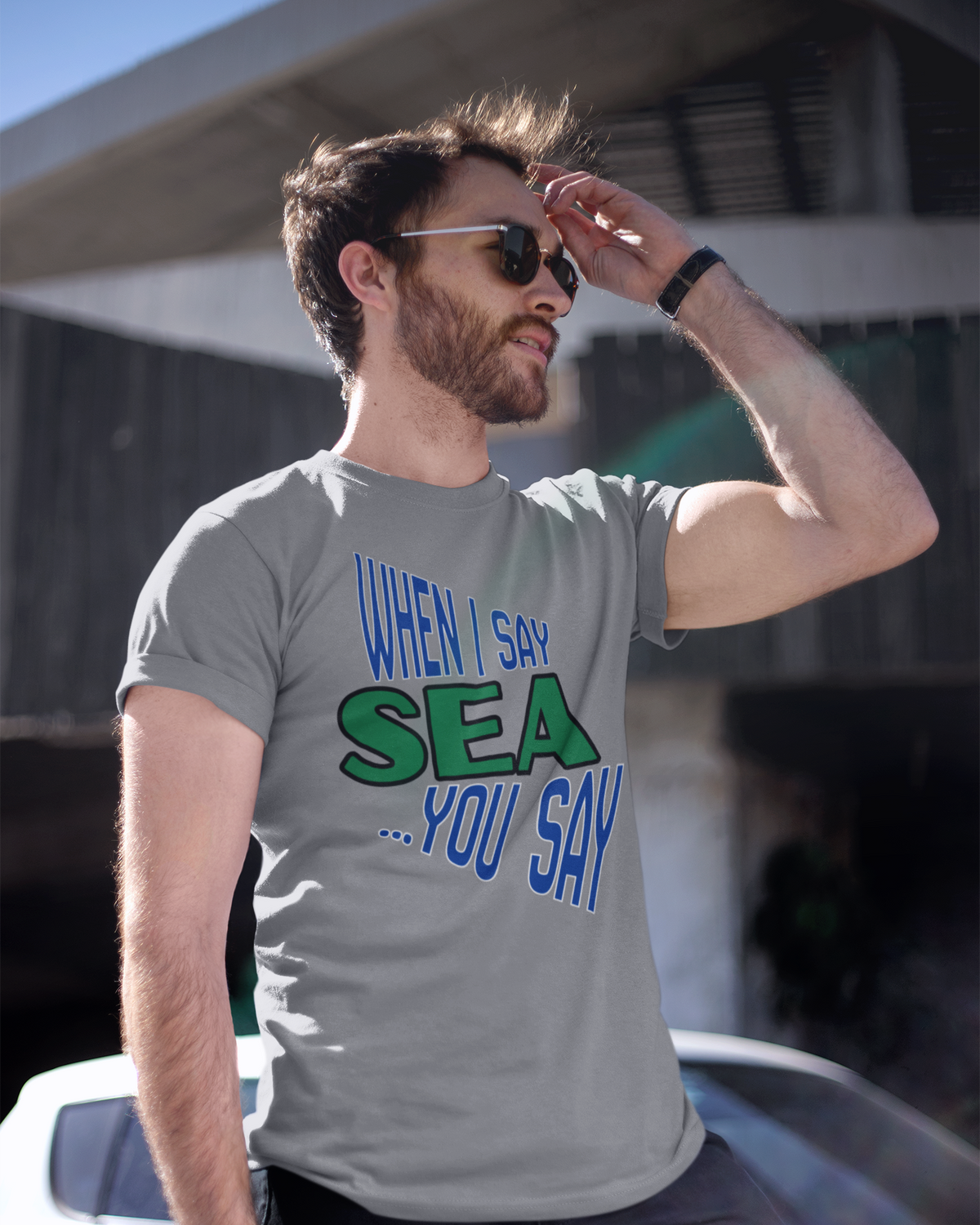 A man wearing a gray graphic t-shirt with the text 'WHEN I SAY SEA .
