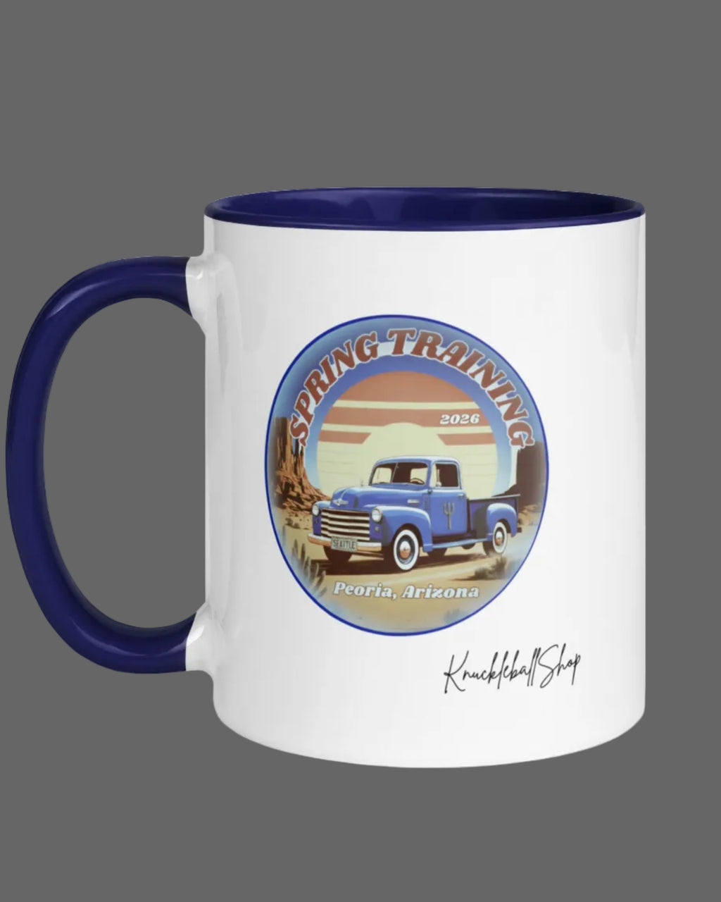 White mug with blue inside and blue handle featuring a spring training emblem, blue truck, trident and Seattle license plate with signature
